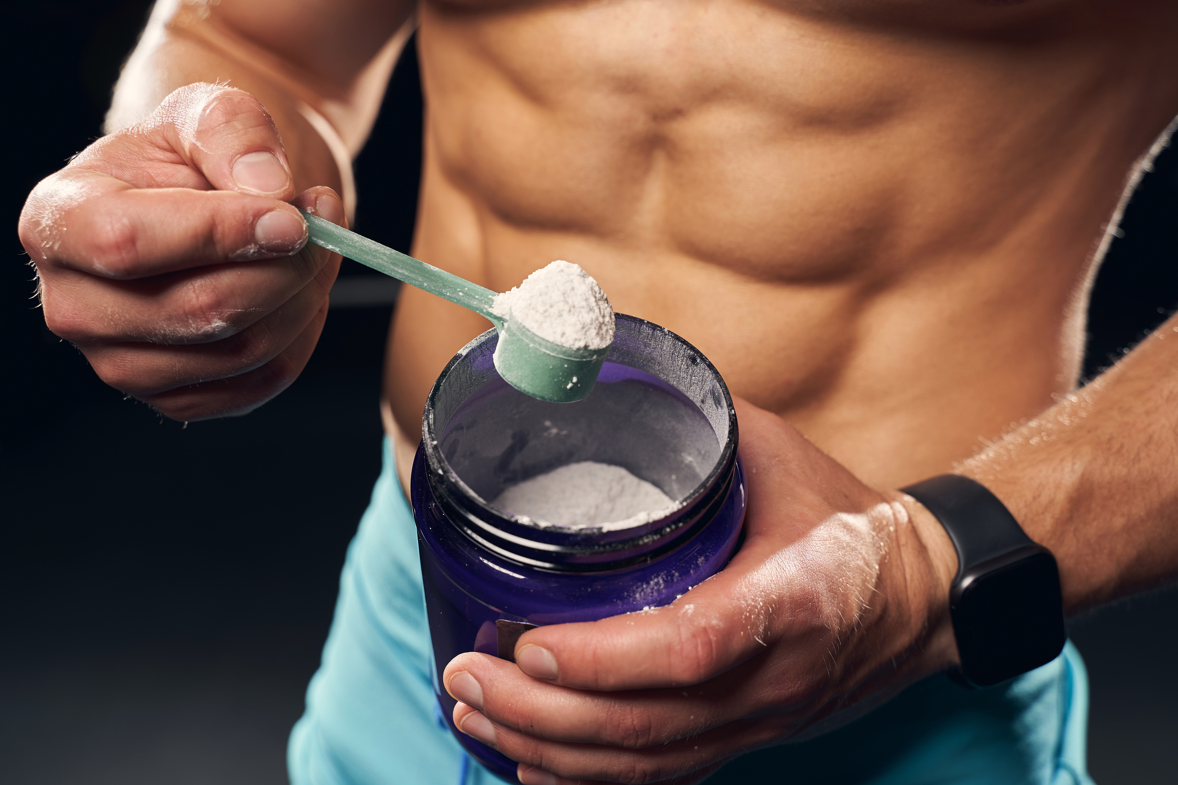 Athletic man holding a container with protein powder